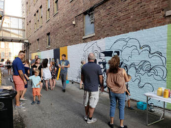 Picture of people in an alley with colorful mural