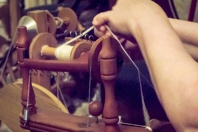 Hands wrapping yarn on a spindle.
