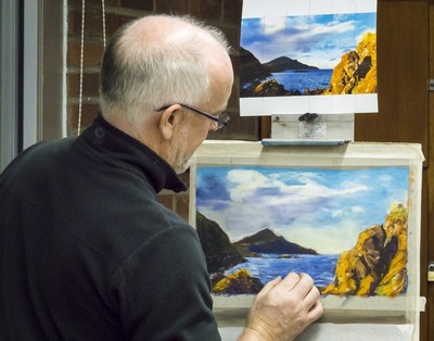 Man facing an easel, recreating a photograph with pastels.
