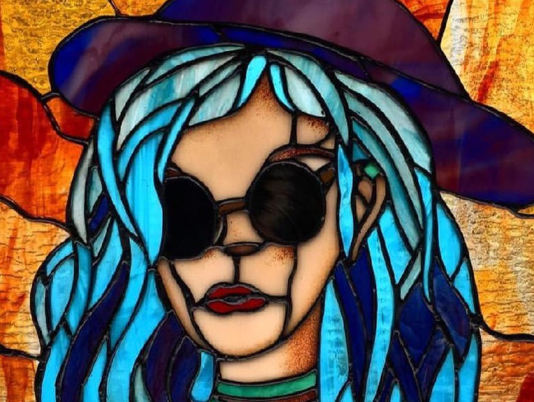 Stained Glass of a person with blue hair, sunglasses, and a hat.